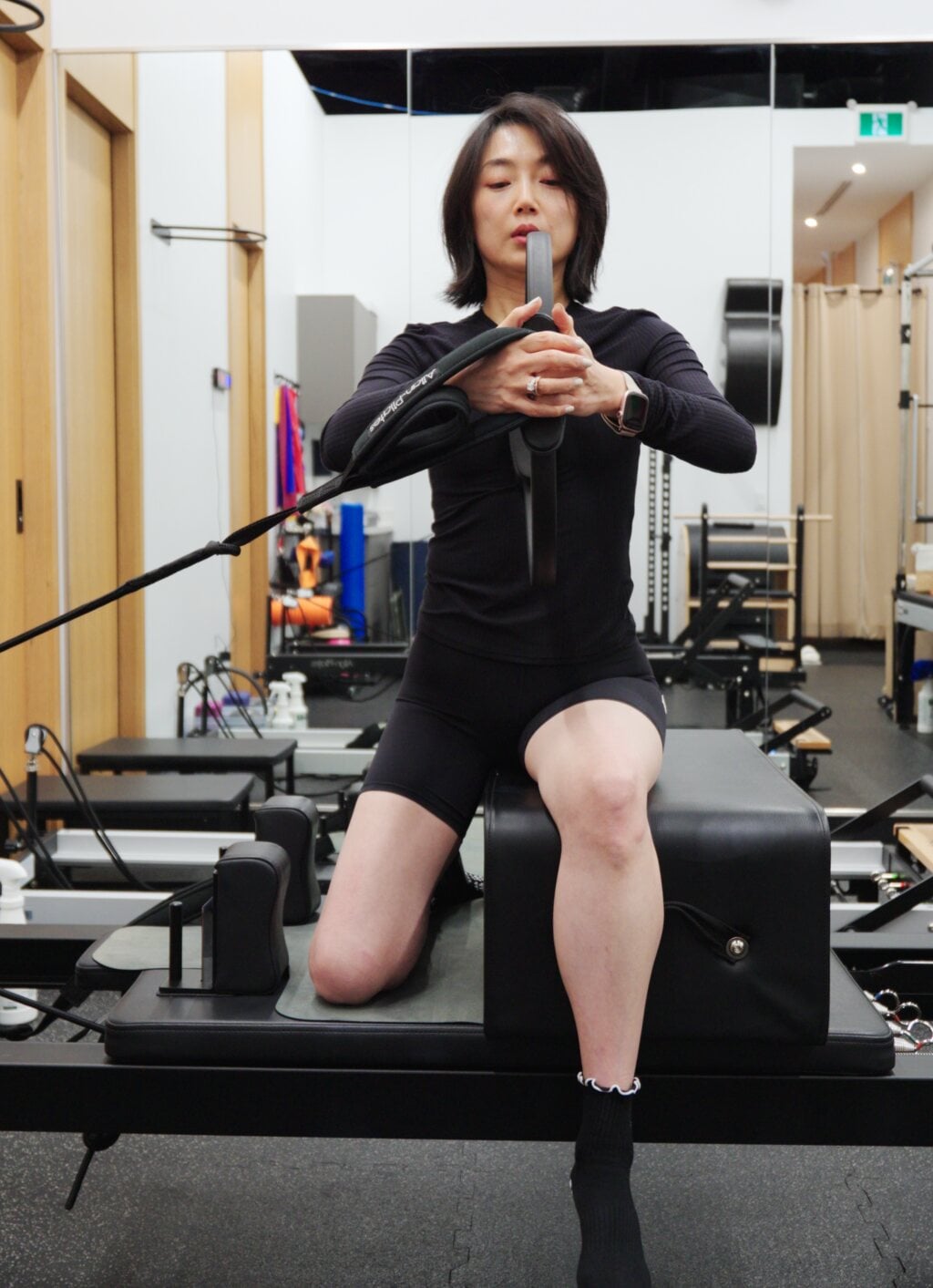 A Pilates instructor demonstrating a seated reformer exercise in the studio at Aurora North Medical Centre in Aurora, Ontario